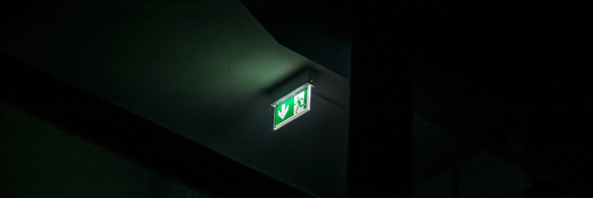 Świecący symbol oświetlenia ewakuacyjnego w ciemnym pomieszczeniu