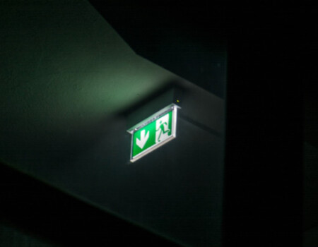 Świecący symbol oświetlenia ewakuacyjnego w ciemnym pomieszczeniu